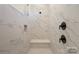 Modern shower with marble tile, a built-in seat, and sleek fixtures at 8605 Carly Ln, Mint Hill, NC 28227