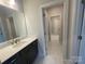 A bright bathroom with white marble flooring, a dark vanity, and a mirror at 9411 Stonebridge Way # 49, Mint Hill, NC 28227