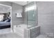 Modern bathroom features a soaking tub with glass enclosure and serene gray tiling at 1290 Kindness Nw Ct, Concord, NC 28027