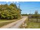 View of a long gravel driveway leading to the property, framed by trees and a wooden fence at 5960/5930 S Main St, Salisbury, NC 28147
