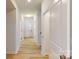 Bright hallway featuring light wood flooring and white doors leading to various rooms at 649 Kitfox Nw Dr, Concord, NC 28027