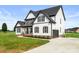 Beautiful two-story white home showcasing a side entry garage, landscaped front yard, and board and batten siding at 2025 Parks Rd, Salisbury, NC 28147