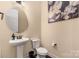 Cozy powder room with a pedestal sink, round mirror, floral artwork, and 'Love You More' sign at 16827 Monocacy Blvd, Huntersville, NC 28078