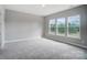 Large bedroom with plush carpet and triple window set providing ample light and wooded views at 552 Fern Hill Rd # 21, Mooresville, NC 28117