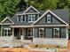 New construction home featuring gray siding, stone accents, black shutters, and a covered front porch at 552 Fern Hill Rd # 21, Mooresville, NC 28117