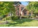 Charming two-story red brick home with manicured lawn and mature trees in a well-kept community at 15909 Woodcote Dr, Huntersville, NC 28078