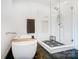 Bright bathroom featuring a walk-in shower, soaking tub, and stylish black and white tile flooring at 2107 W Trade St, Charlotte, NC 28216