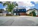 Unique, modern two-story home with a black exterior, beautiful landscaping, and a stained wood garage door at 2107 W Trade St, Charlotte, NC 28216