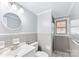 Clean bathroom with grey tile, a shower, and a vanity with a round mirror at 3327 Deerwood Dr, Gastonia, NC 28054