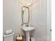 Bright powder room showcasing a pedestal sink with brass fixtures and stylish mirror at 8111 Farm Crossing Ln # 2, Huntersville, NC 28078