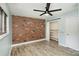 Bright bedroom with brick accent wall, wood-look floors, and ceiling fan at 1201 Green Oaks Ln # G, Charlotte, NC 28205