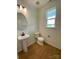 Small powder room with pedestal sink and hardwood floors at 3018 Cunningham Farm Dr, Indian Trail, NC 28079