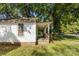 Side view of a white house needing renovation, showing brick foundation and porch at 3444 Marvin Rd, Charlotte, NC 28211