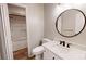 Bright bathroom featuring a white sink, wood-look floors, round mirror, and a shower-tub combination at 1000 Hunting Ave, Lincolnton, NC 28092