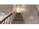 Carpeted staircase with wooden handrail, providing a welcoming transition to the upper level at 1000 Hunting Ave, Lincolnton, NC 28092