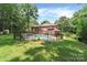 Spacious backyard featuring a swimming pool, lounge chairs, mature trees, and privacy fence at 1134 Willow Oaks Trl, Matthews, NC 28104