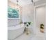 Bright bathroom featuring a freestanding tub, tiled accent wall, and modern chandelier at 1134 Willow Oaks Trl, Matthews, NC 28104