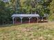 Metal roofed barn with a wood structure nestled in a green field at 13079 Philadelphia Church Rd, Oakboro, NC 28129