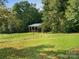 Metal roofed barn with a wood structure nestled in a green field at 13079 Philadelphia Church Rd, Oakboro, NC 28129