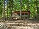 A charming wooden chicken coop is nestled among mature trees in a wooded backyard setting at 13079 Philadelphia Church Rd, Oakboro, NC 28129