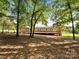 Back view of the single-story home, highlighting its large deck surrounded by mature trees and greenery at 13079 Philadelphia Church Rd, Oakboro, NC 28129