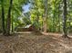 Exterior view of rustic cabin surrounded by mature trees and a stone fire pit in a natural, wooded setting at 13079 Philadelphia Church Rd, Oakboro, NC 28129