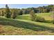 Lush green field with mature trees and a red barn in the distance at 13079 Philadelphia Church Rd, Oakboro, NC 28129