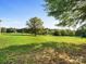 Expansive lush green field with mature trees and a fenced perimeter on a sunny day at 13079 Philadelphia Church Rd, Oakboro, NC 28129