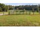 Green metal gate with wooden posts opening into a grassy field with a driveway at 13079 Philadelphia Church Rd, Oakboro, NC 28129