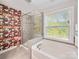 Modern bathroom showcasing a glass-enclosed shower, soaking tub, and bright window at 2657 Cheverny Pl, Concord, NC 28027