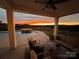 Cozy covered patio with comfortable seating, overlooking a beautiful pool and scenic landscape at sunset at 7248 Waterwheel Sw St, Concord, NC 28025