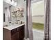 Bathroom with a modern vanity, decorative shelves, and a bright window with sheer curtains at 1109 Freeman View Dr, Albemarle, NC 28001