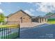 Brick home with a manicured backyard, defined by rocks, landscaping, and a wrought iron fence at 2014 Newstyle Way, Tega Cay, SC 29708