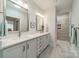 Bright bathroom featuring double sinks, white cabinets, modern fixtures, and a walk-in shower with tiled walls at 2014 Newstyle Way, Tega Cay, SC 29708