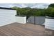A home's rooftop deck features wood-look planks and black metal railing with views of the surrounding trees and cloudy skies at 2031 Belmont Terraces Ln # 6, Charlotte, NC 28205