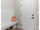 Well-organized mudroom with a bench, coat hooks, storage, and a bright white door at 7059 Duncan Acres Dr, Belmont, NC 28012