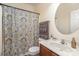 Well-maintained bathroom with a wood vanity, oval mirror, and shower-tub combination with patterned curtain at 10080 Highland Creek Cir, Indian Land, SC 29707