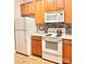 Functional kitchen with wood cabinets, white appliances, and mosaic backsplash at 11264 Hyde Pointe Ct, Charlotte, NC 28262