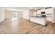 An open-concept living space with wood flooring, a kitchen featuring white cabinets, a black counter, and stainless-steel appliances at 112 Dorian Pl, Troutman, NC 28166