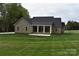 Home exterior with a covered porch, light tan siding, well-maintained lawn, and landscaping at 1117 Shadowmoss Ct, Salisbury, NC 28147