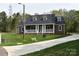 Inviting brick house with a covered front porch, green lawn, and paved driveway at 1117 Shadowmoss Ct, Salisbury, NC 28147