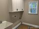 Clean laundry room with white cabinets, sink, and a view to the backyard at 1117 Shadowmoss Ct, Salisbury, NC 28147