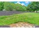 Green backyard featuring grassy slope with mulch, trees and sky, stone steps at base at 5832 Amity Springs Dr, Charlotte, NC 28212