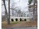 A single-level home featuring a gravel driveway lined with bushes and surrounded by leafless trees at 1926 Scenic Dr, Iron Station, NC 28080