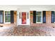 Close-up of a welcoming front porch featuring a red door, brick facade, and mosaic tile flooring at 5444 Marengo Cir, Charlotte, NC 28216