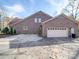 Brick house featuring attached garage with a concrete driveway and landscaping at 909 Woodhurst Dr, Monroe, NC 28110