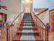 A carpeted staircase with wooden railing leads to the second floor with ample natural light at 909 Woodhurst Dr, Monroe, NC 28110