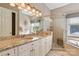 Bright bathroom with double vanity, granite countertops, framed mirror, a glass-enclosed shower and tub at 9723 Sedgefield Dr, Waxhaw, NC 28173
