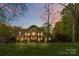 Elegant two-story brick home featuring manicured lawn and mature trees at twilight at 9723 Sedgefield Dr, Waxhaw, NC 28173