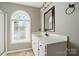 Bathroom featuring a single sink vanity with white countertop, dark hardware, and an arched window at 3007 Gambrill Falls Dr, Indian Trail, NC 28079